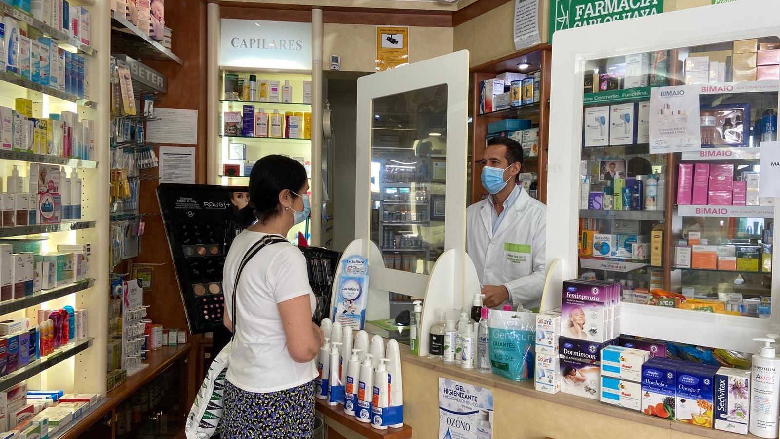Francisco Criado atiende a una clienta en su farmacia de la avenida Carlos Haya.