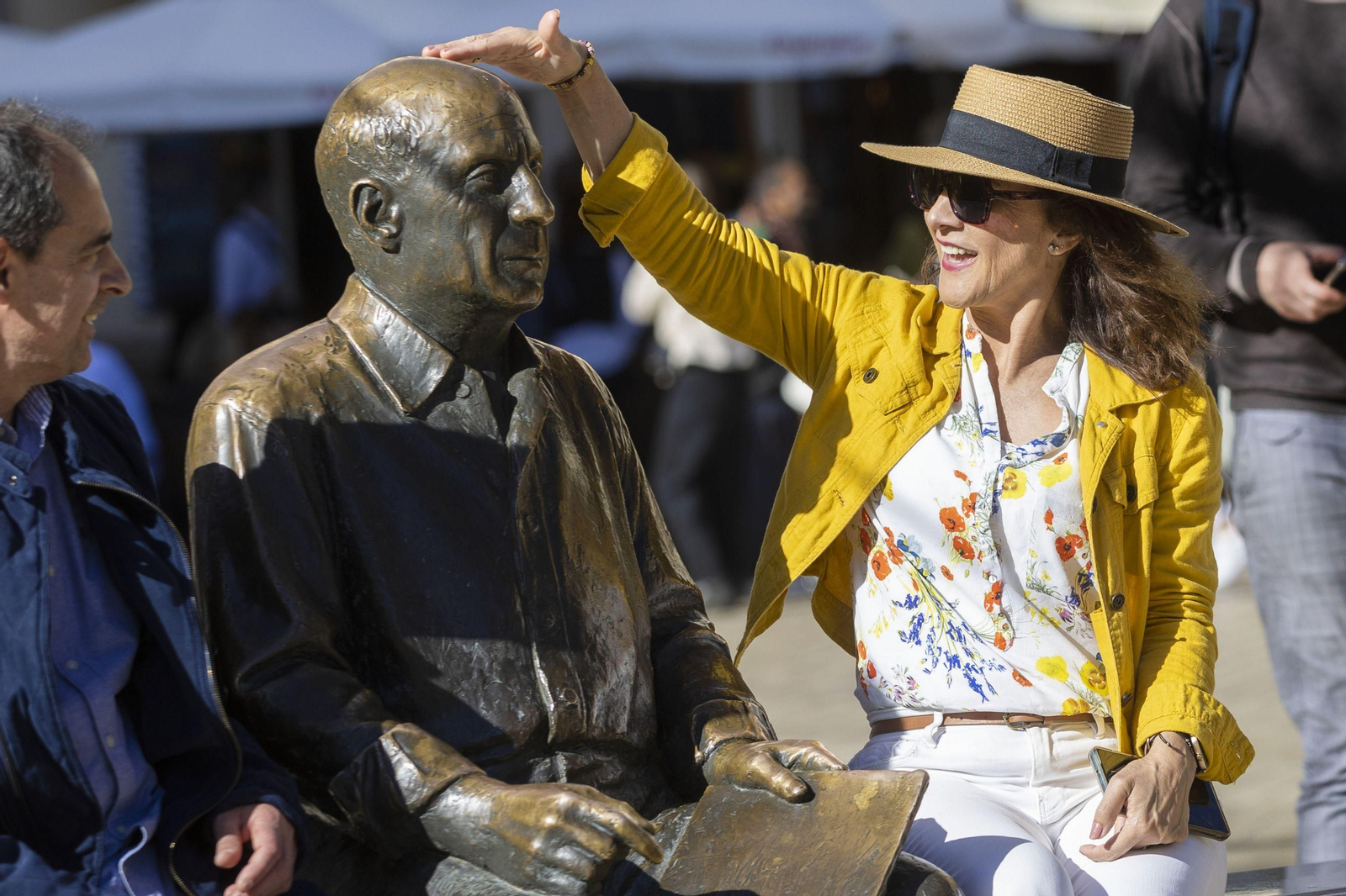 Unos turistas se sientan junto a la estatua de Pablo Ruiz Picasso, en la Plaza de la Merced.