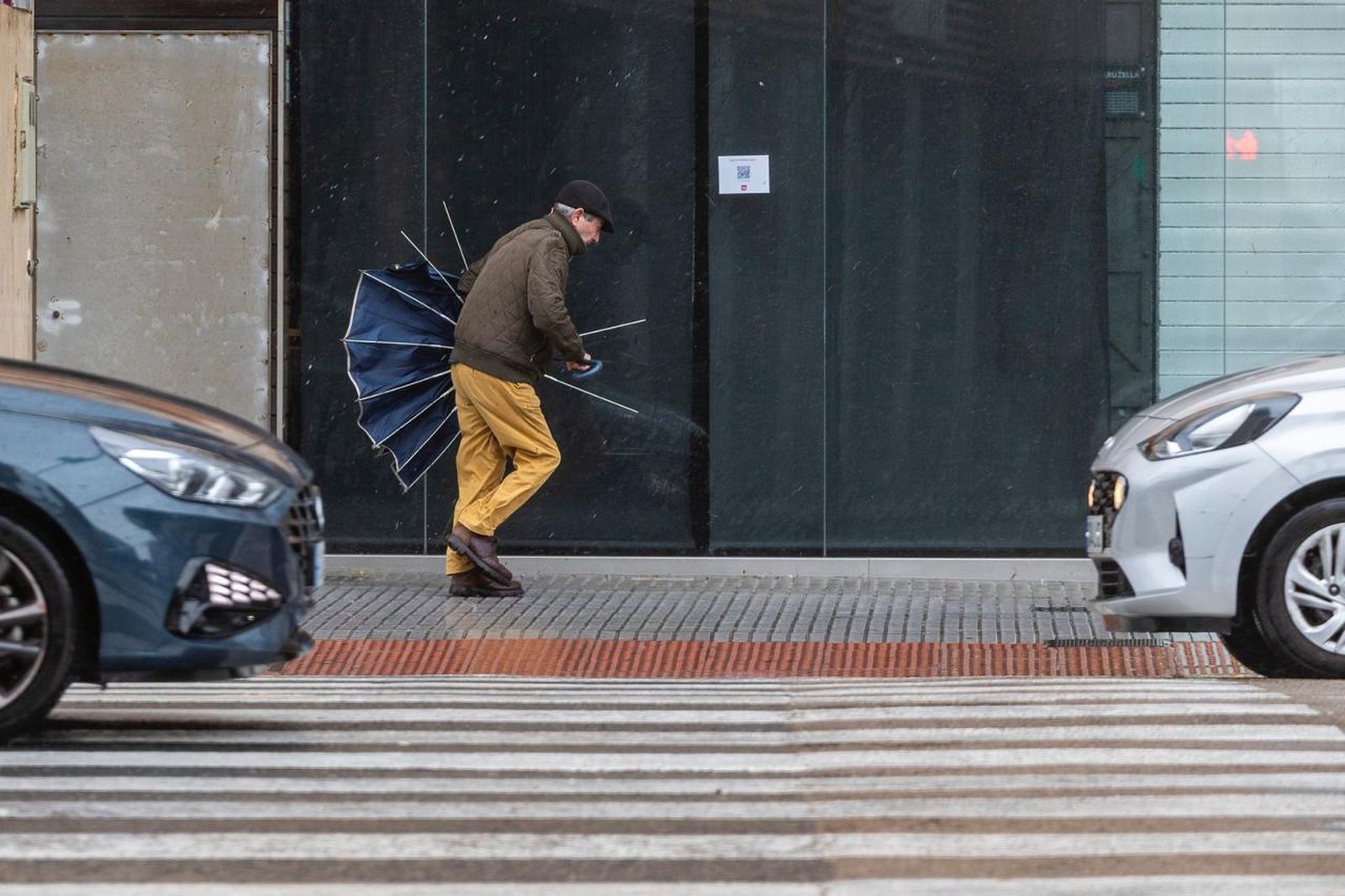 Un hombre camina por Cádiz con el paraguas roto en un día de viento muy fuerte en la ciudad.