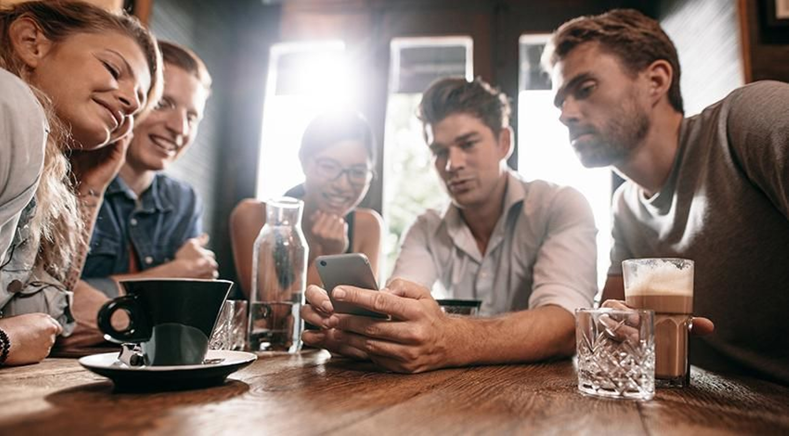 Grupo de amigos atentos a la pantalla de un smartphone.