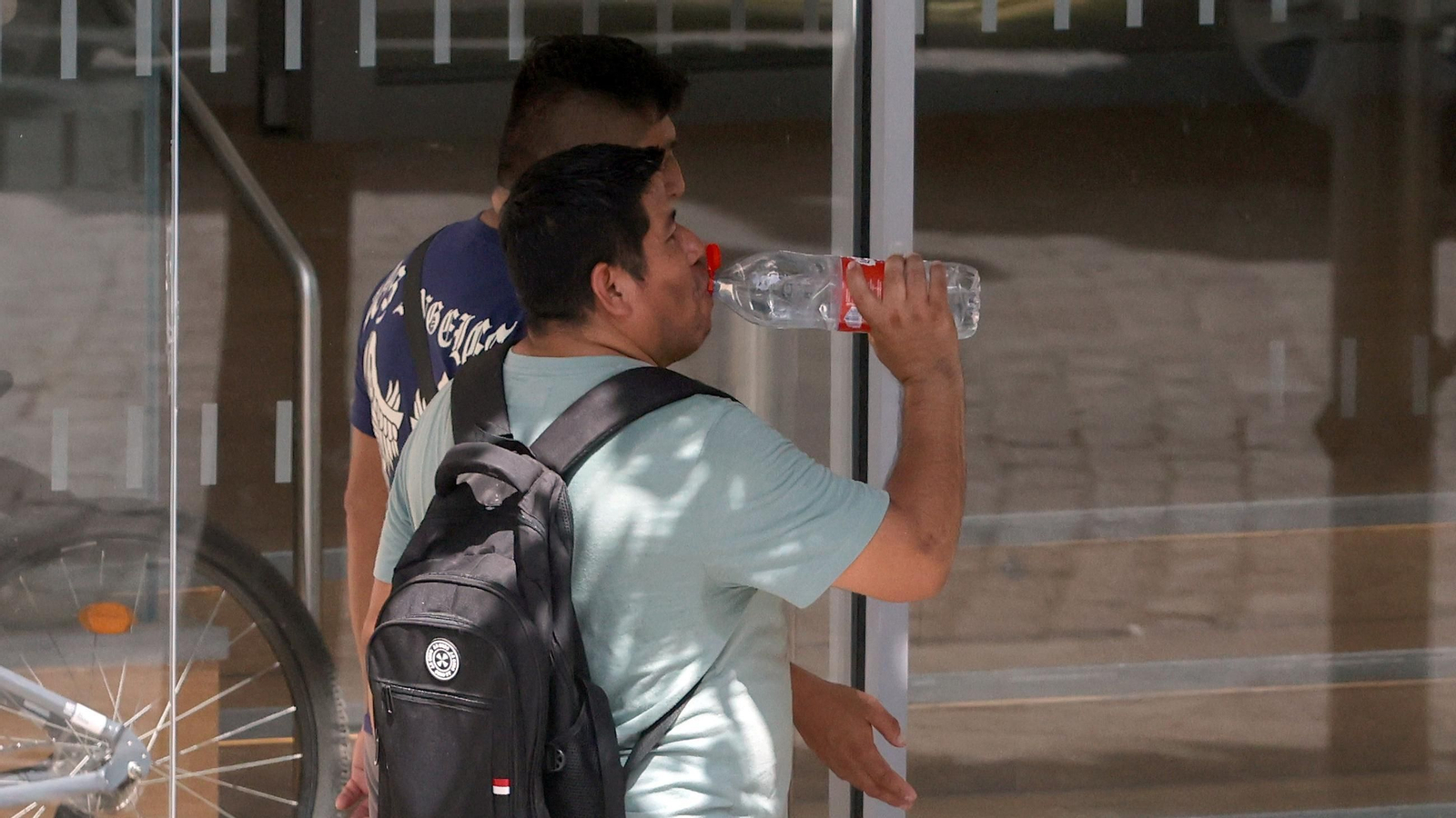 Un hombre se refresca con una botella de agua mientas camina por la sombra en una calle de Jerez