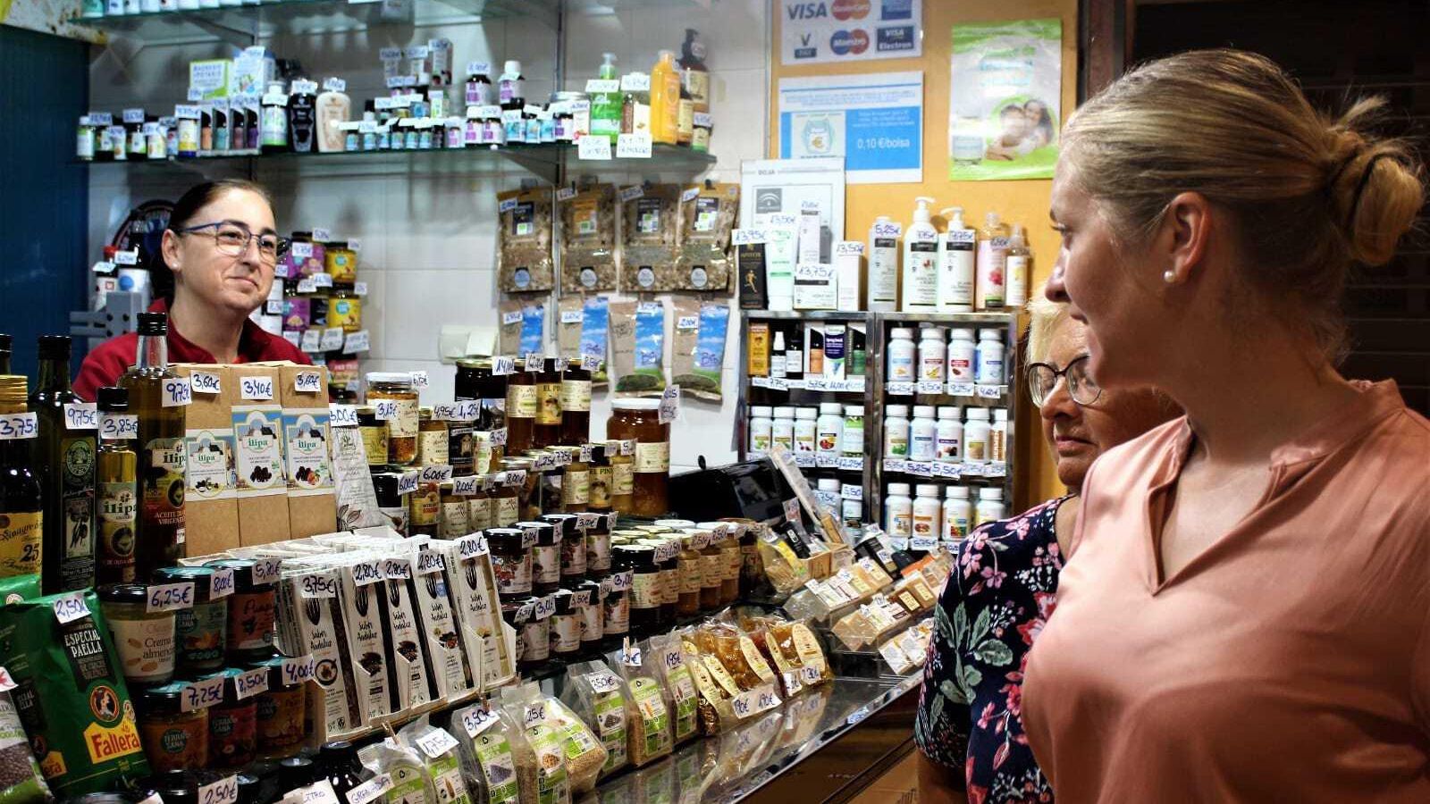 María del Mar atendiendo a dos clientas en su puesto de productos naturales