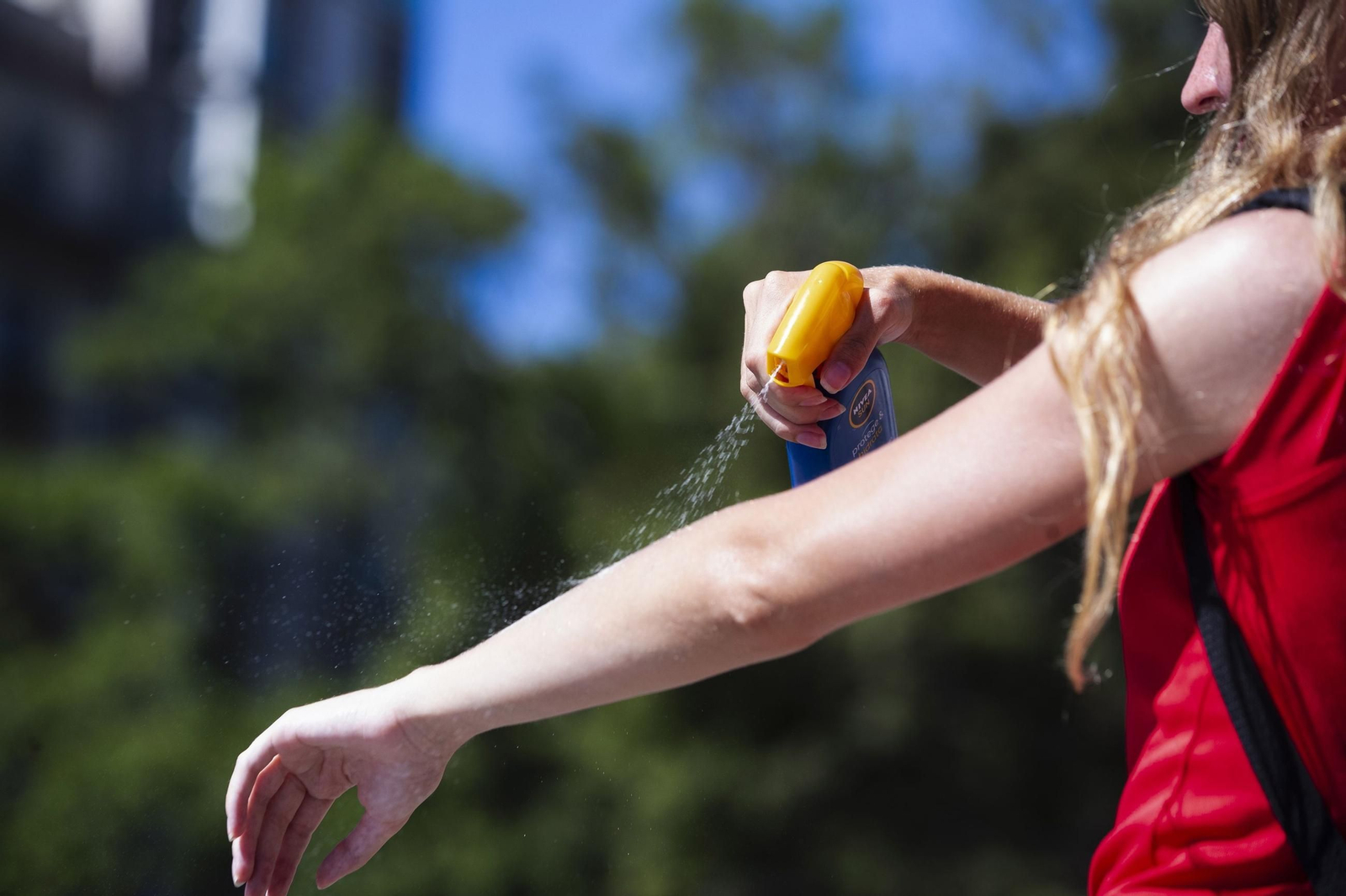 Chica echándose crema solar.