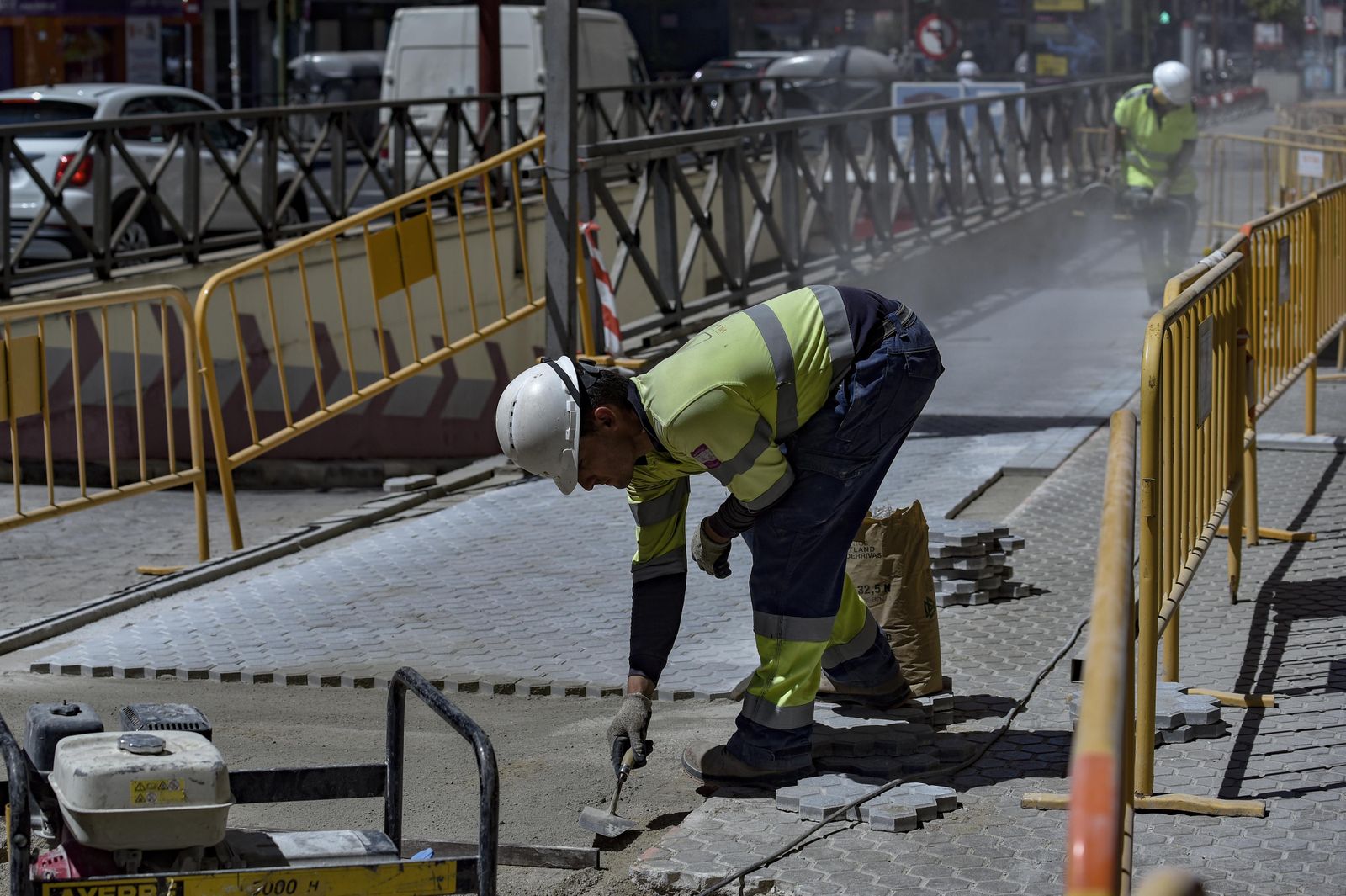 Dos albañiles trabajan en un acerado del barrio de Los Remedios.