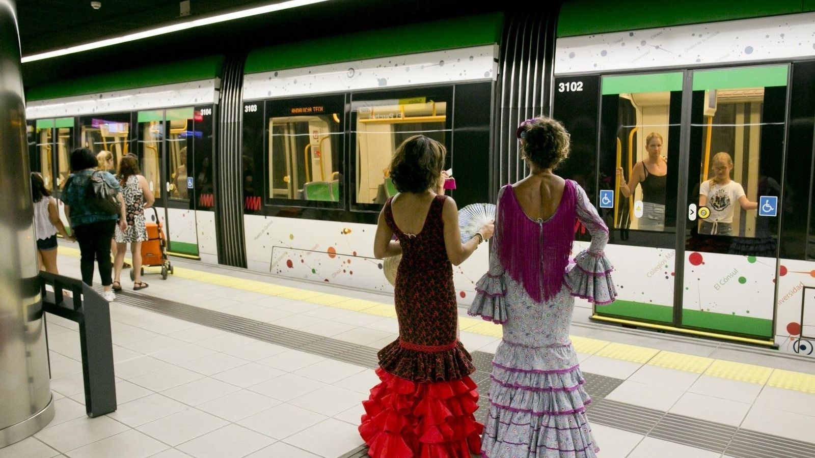 Dos mujeres con vestidos flamencos junto al Metro de Málaga.