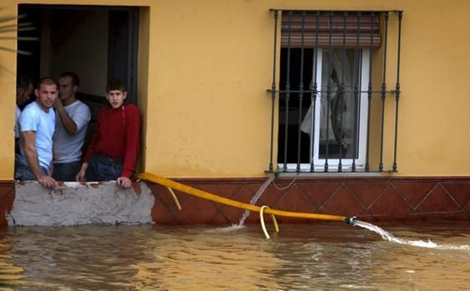 Una familia de Tocina utiliza una manguera para achicar el agua de su casa.

Foto: Agencias