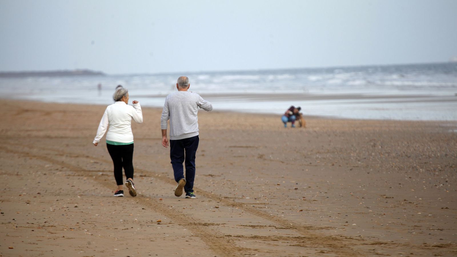 Una pareja pasea por la playa durante la desecalada.
