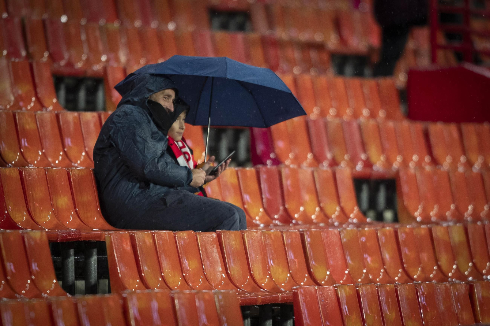 Dos aficionados bajos el paraguas en la vacía grada del Nuevo Los Cármenes en el choque ante el Albacete