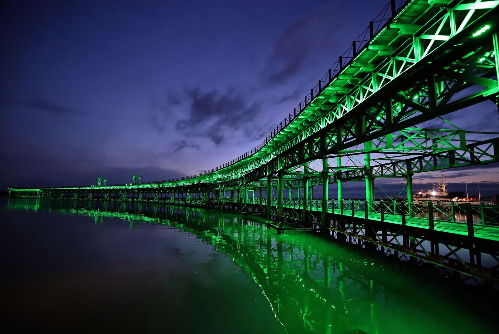 El muelle de la Riotinto se ilumina de verde en el día mundial contra el cancer