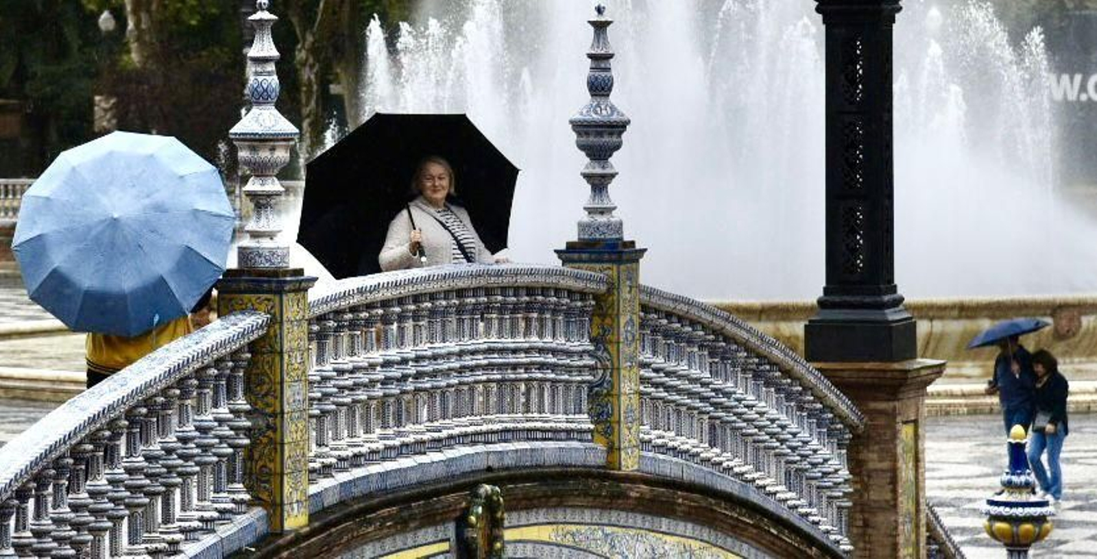 Turistas visitan la Plaza de España de Sevilla bajo la lluvia