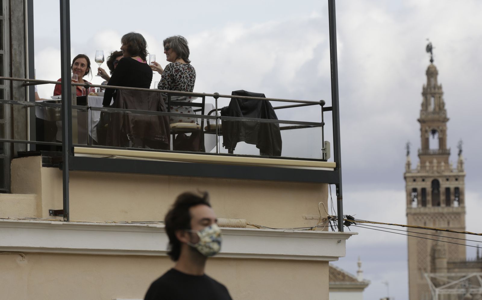 Varias personas brindan en una terraza, con la Girlada al fondo.