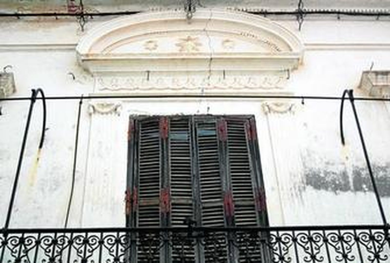 Detalle de la fachada en la que aparece el hueco central de la misma con un balcón corrido y con elementos de hierro forjado.