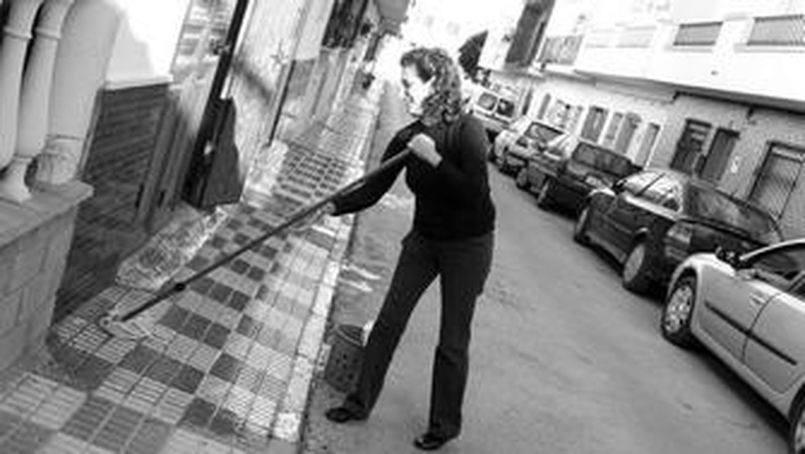 Una mujer limpia la acera de su vivienda en la calle América de Los Barrios, el pasado martes.