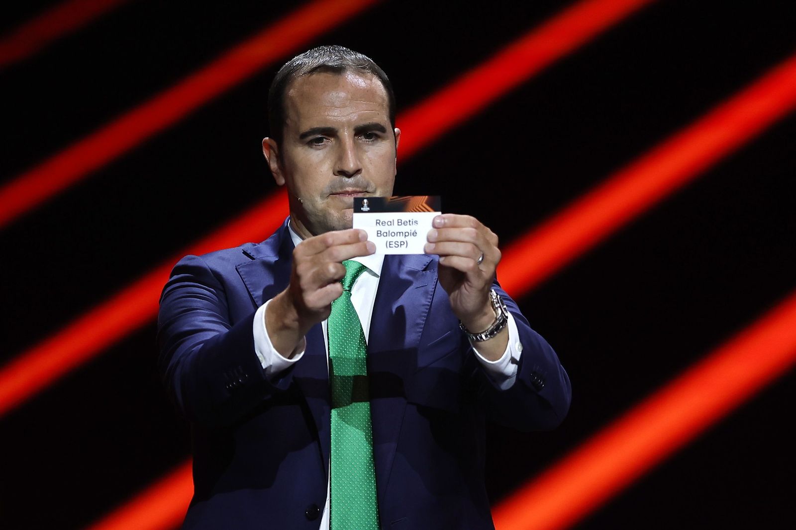 El ex jugador irlandés John O'Shea muestra la papeleta del Betis en el sorteo.