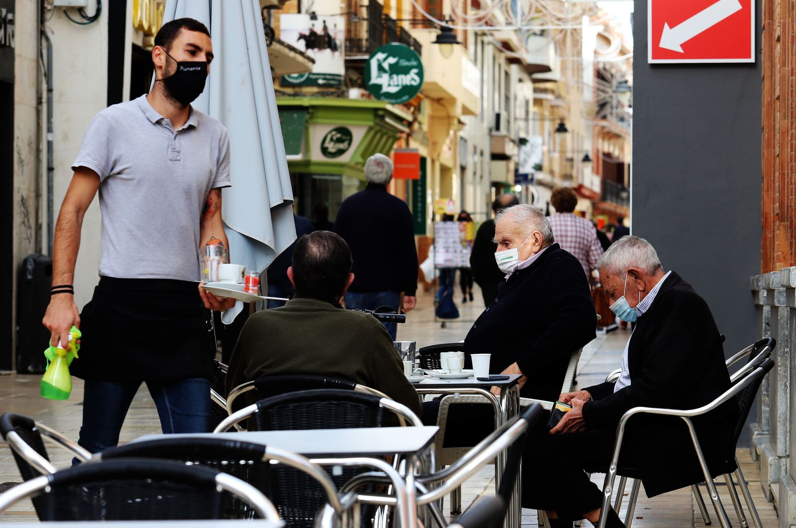Un camarero atiende a varias personas en un establecimiento de la calle Palacio.