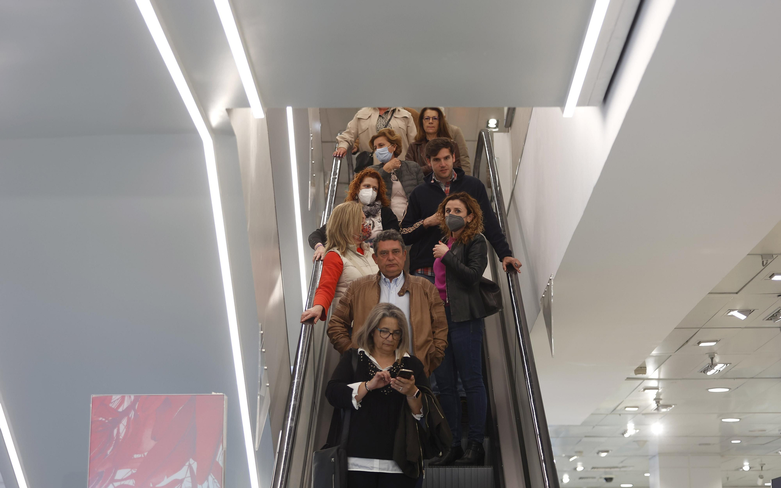 Varias personas con mascarilla y sin ellas en las escaleras mecánicas de El Corte Inglés de la Plaza del Duque.
