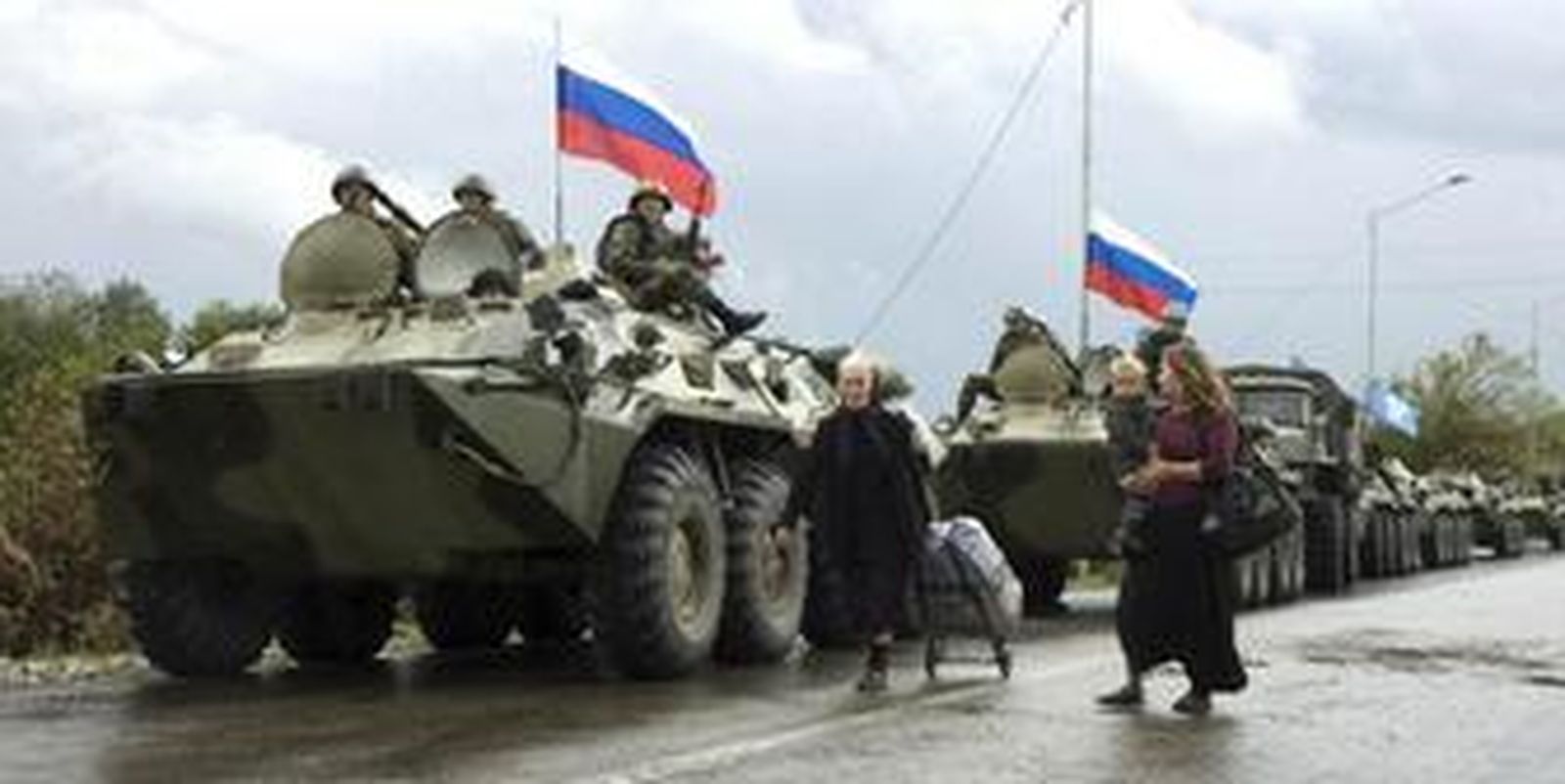 Ciudadanos georgianos pasan por delante de un convoy ruso dispuesto a salir del territorio ocupado.