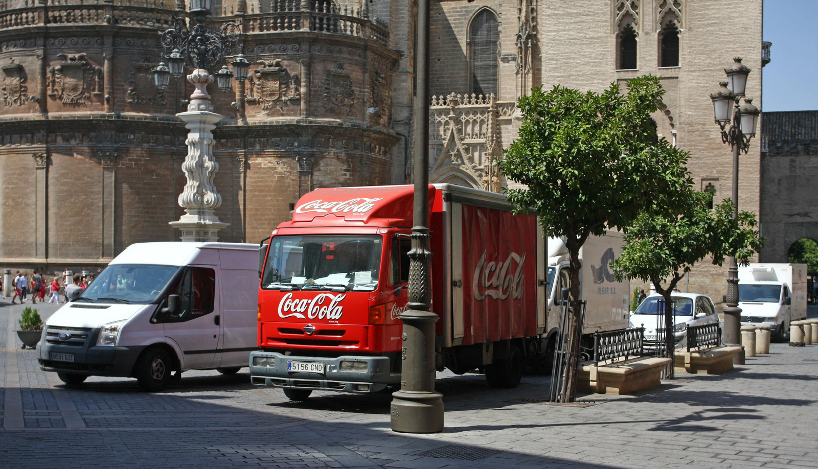Varios vehículos de transporte de mercancías estacionados en la Plaza Virgen de los Reyes ante la Catedral.