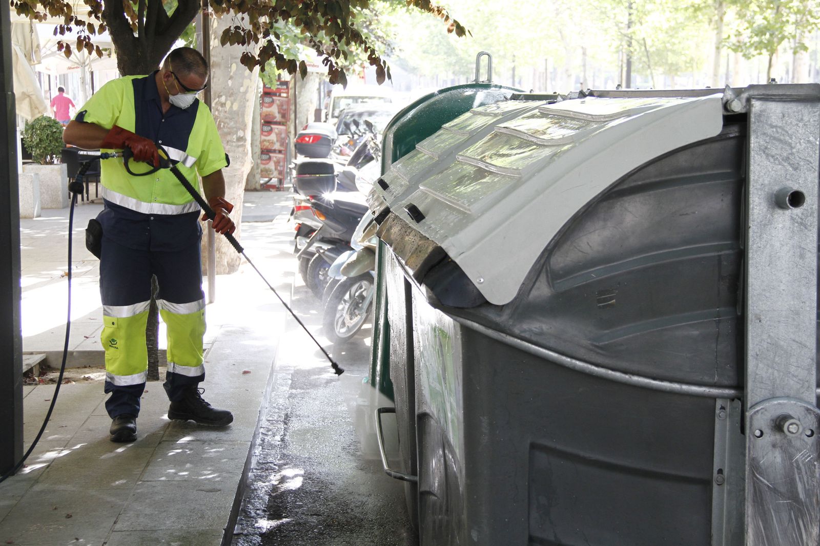 Un operario limpia con agua a presión la calle.
