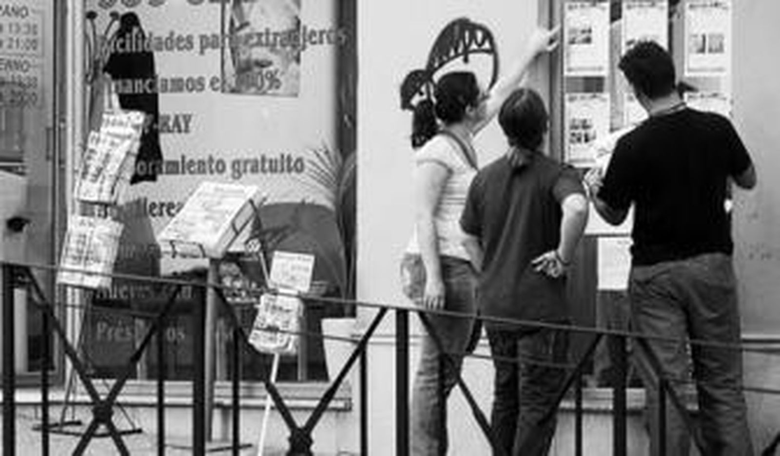 Tres jóvenes consultan la oferta de una inmobiliaria en la provincia de Sevilla.