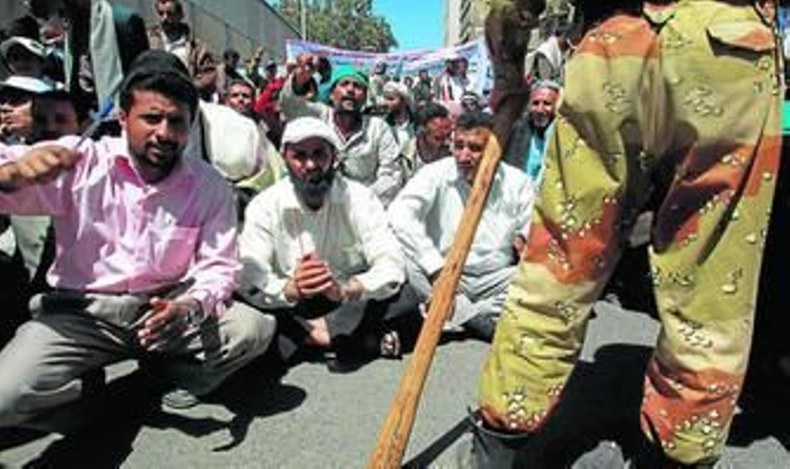 Jóvenes yemeníes participan en las protestas contra Saleh vigilados por militares armados de material antidisturbios