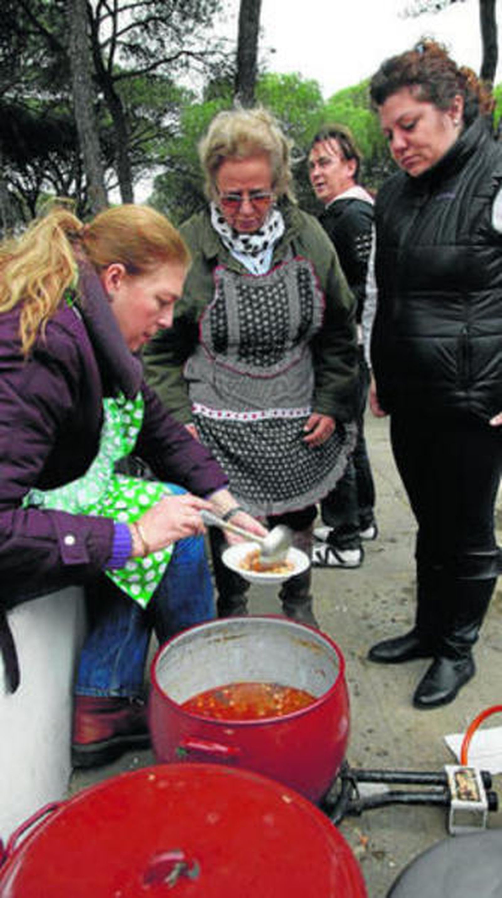 1. Una de las cocineras aparta de la olla una ración del exquisito potaje rociero. 2. La pequeña Rocío, postrada en silla de ruedas desde su nacimiento. 3 y 4. Cientos de cartayeros participaron en la degustación.