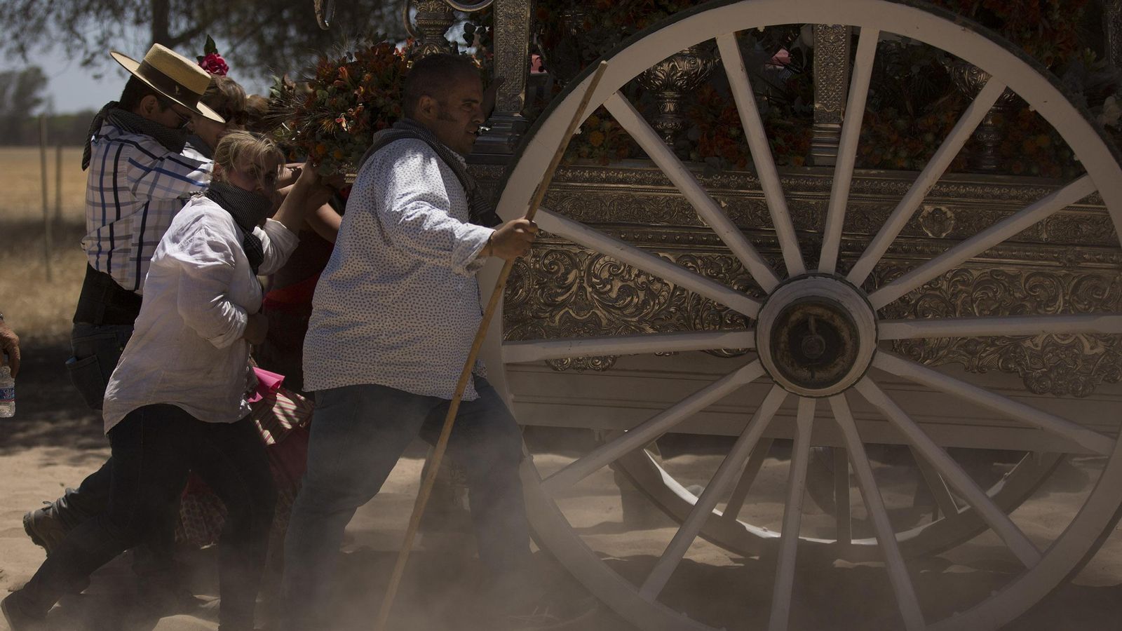Varios peregrinos empujan una carreta de simpecado en el dificultoso transitar por las arenas.