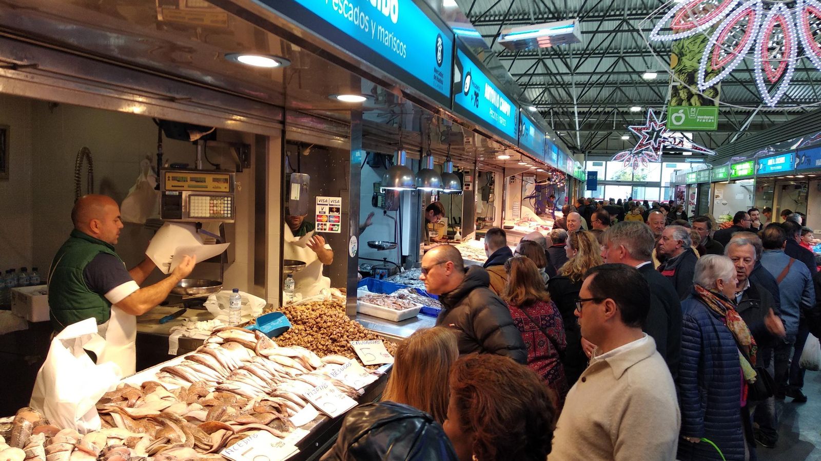 Los clientes miran el producto en uno de los puestos de pescado.