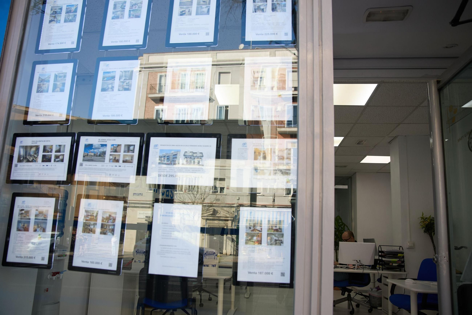 Anuncios de venta de viviendas en el escaparate de una inmobiliaria.