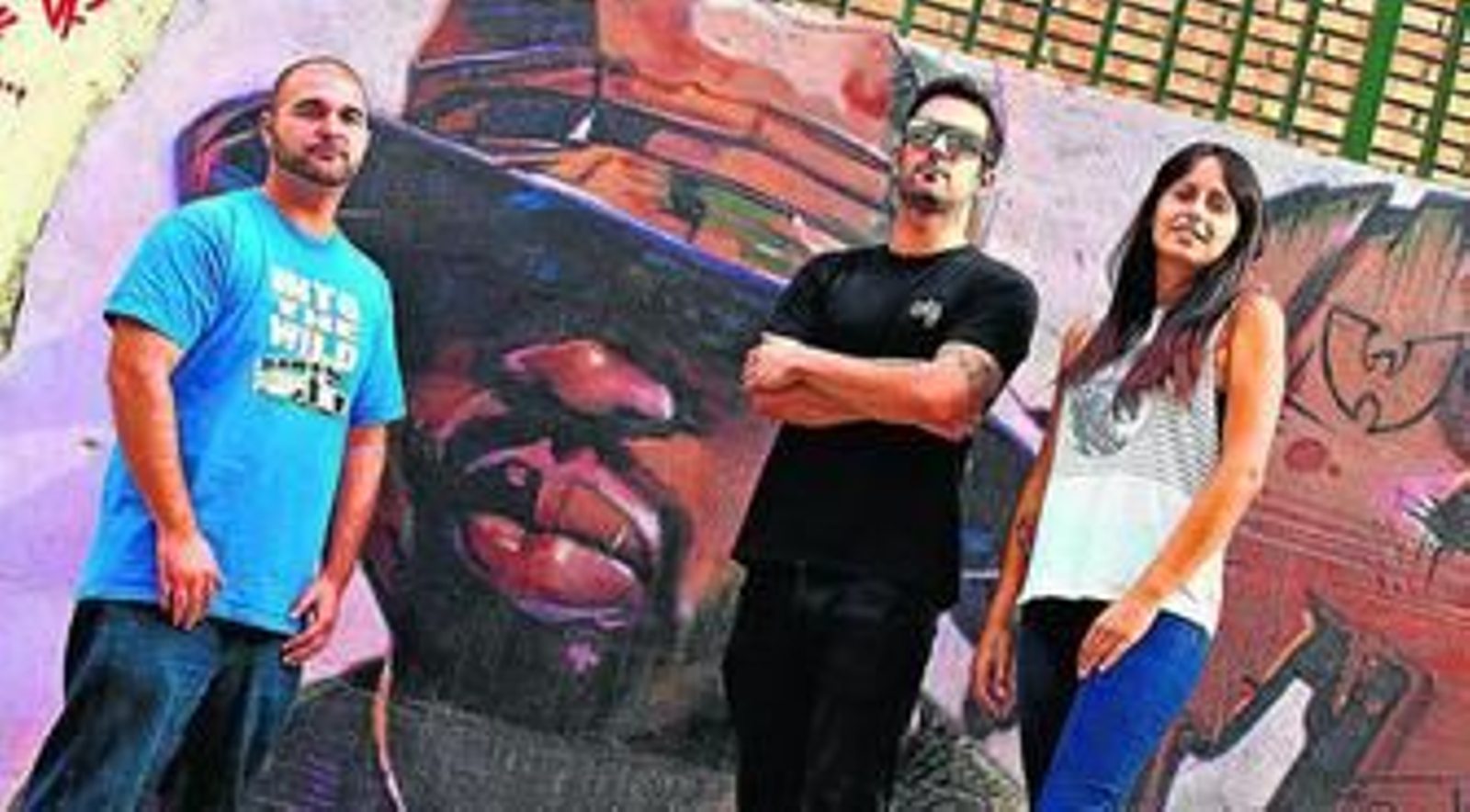 Hidetwo, Lolo Moreno y Ana Balbuena posan frente a uno de los graffitis del artista malagueño, donde se observa el rostro del rapero estadounidense 50 Cent.