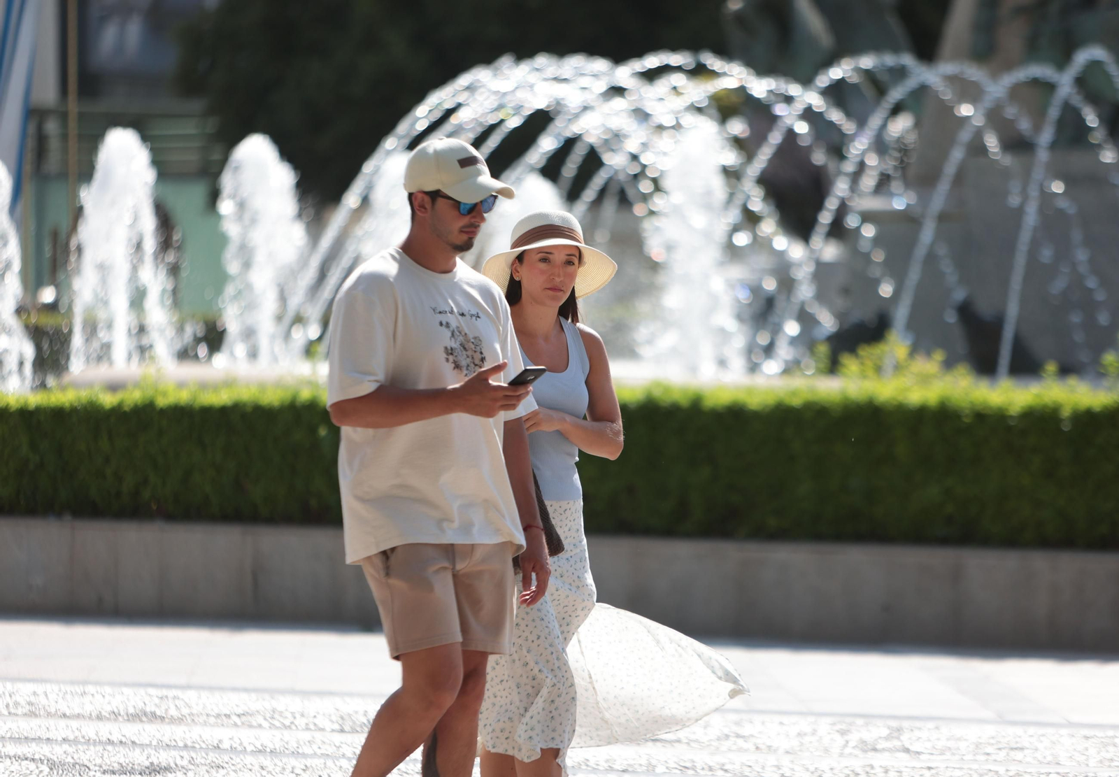 Una pareja camina en la plaza del Arenal de Jrez con gorra y sombrero para protegerse del sol