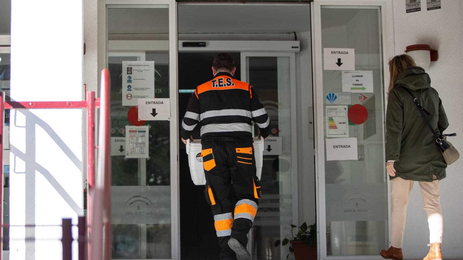 Un técnico sanitario carga con una nevera llena de dosis, en la residencia Heliópolis de Sevilla.