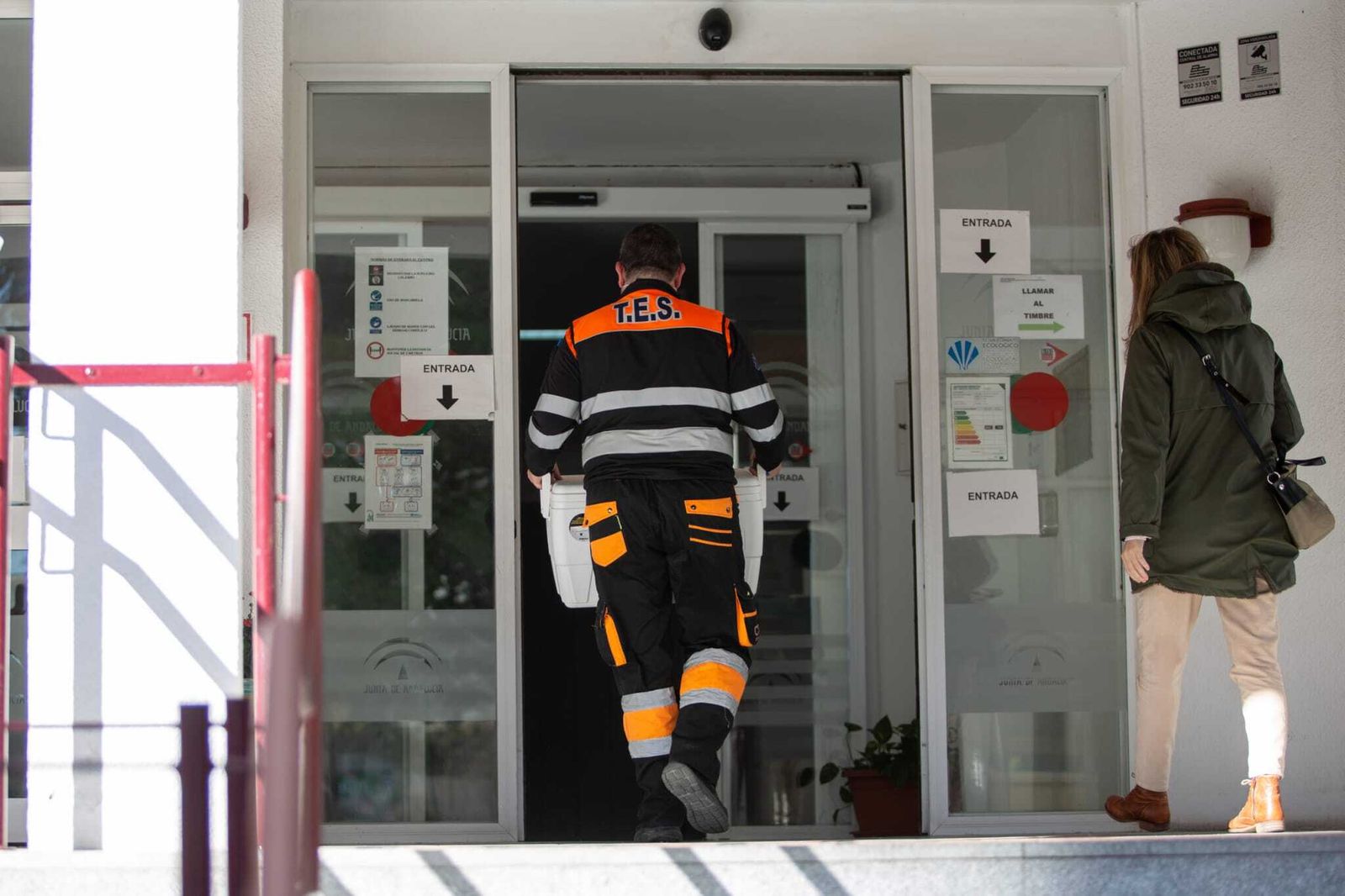 Un técnico sanitario carga con una nevera llena de dosis, en la residencia Heliópolis de Sevilla.