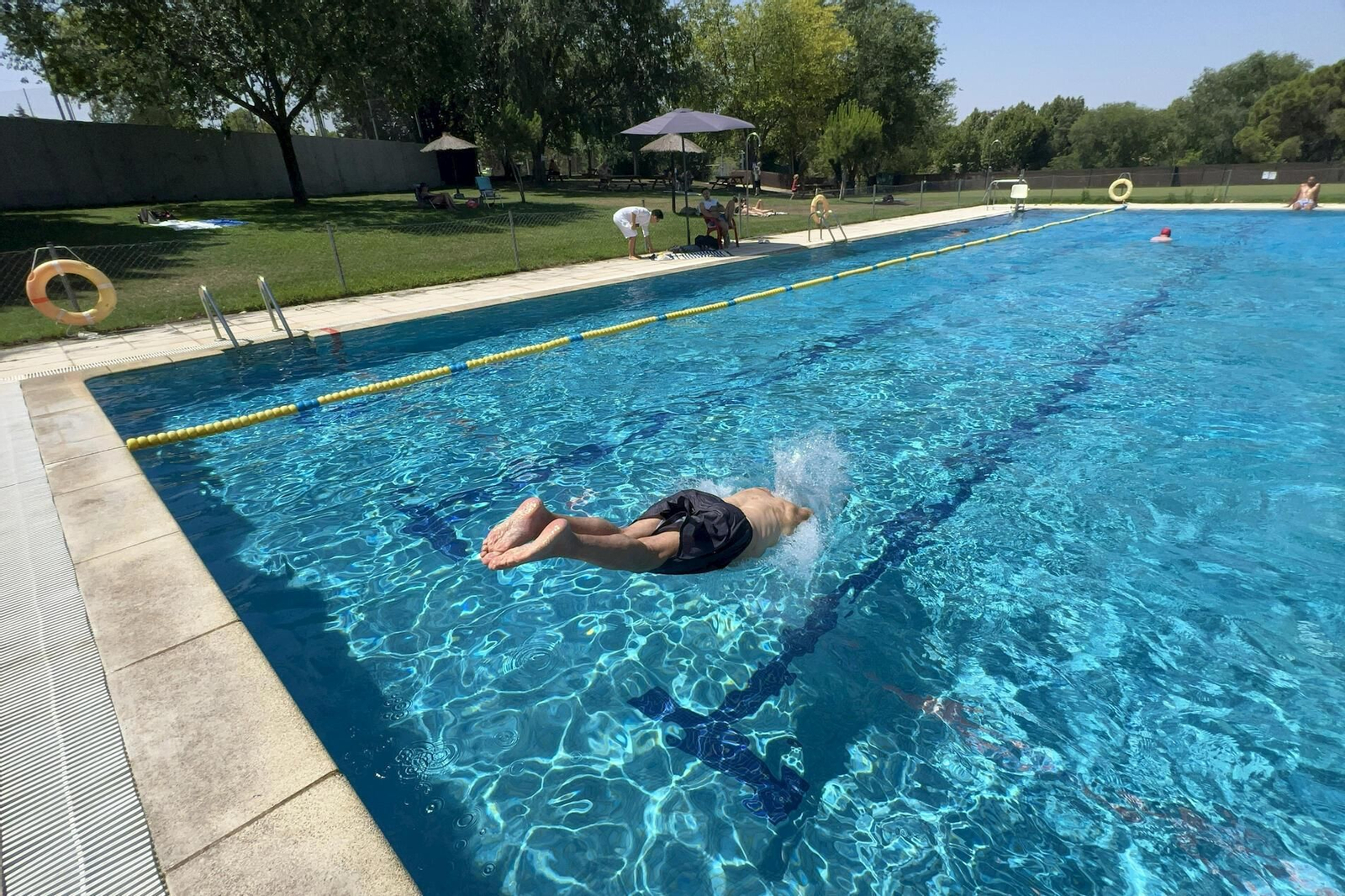Un hombre se zambulle en una piscina. Un hombre se zambulle en una piscina.