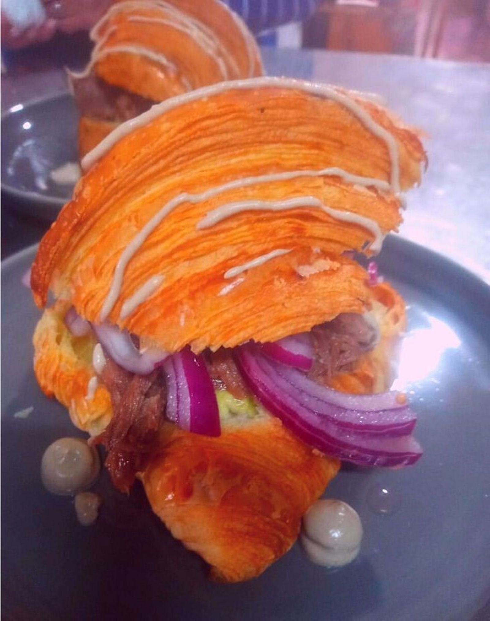 Carrillada al curry rojo, cebolla morada y pepinillos, envuelto en croissant