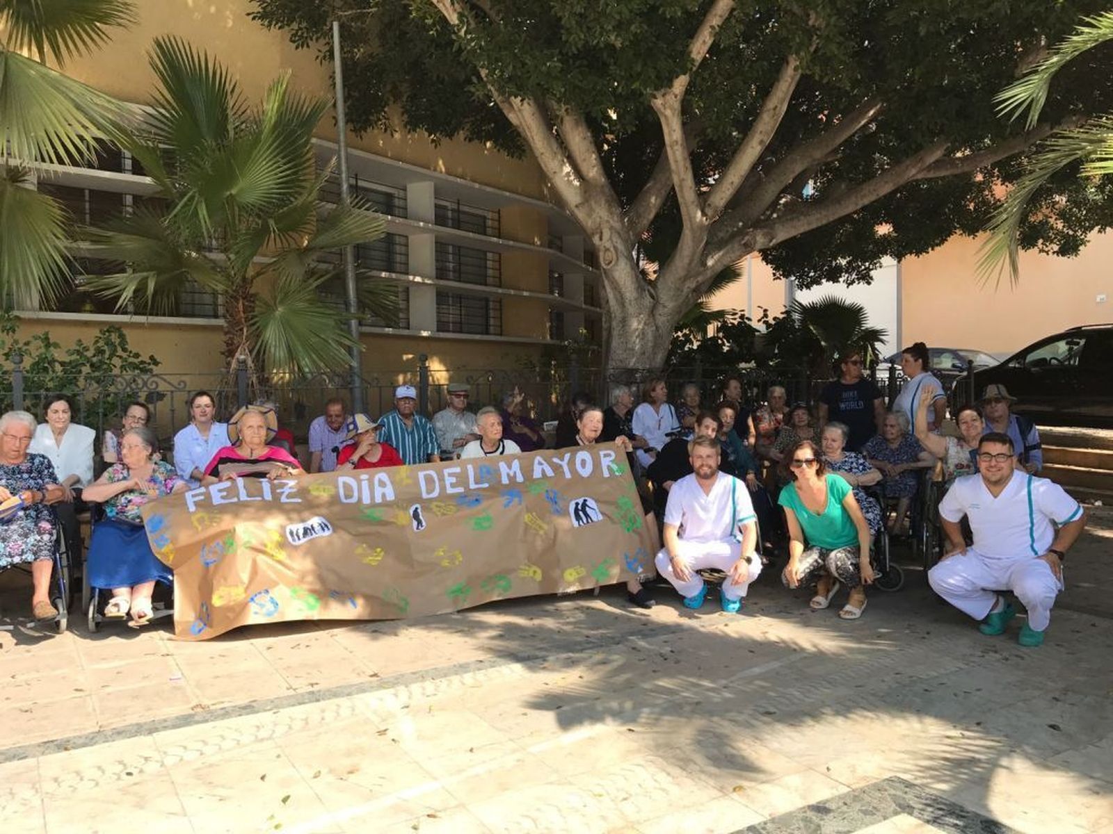 Los mayores y sus monitores posan con la pancarta.