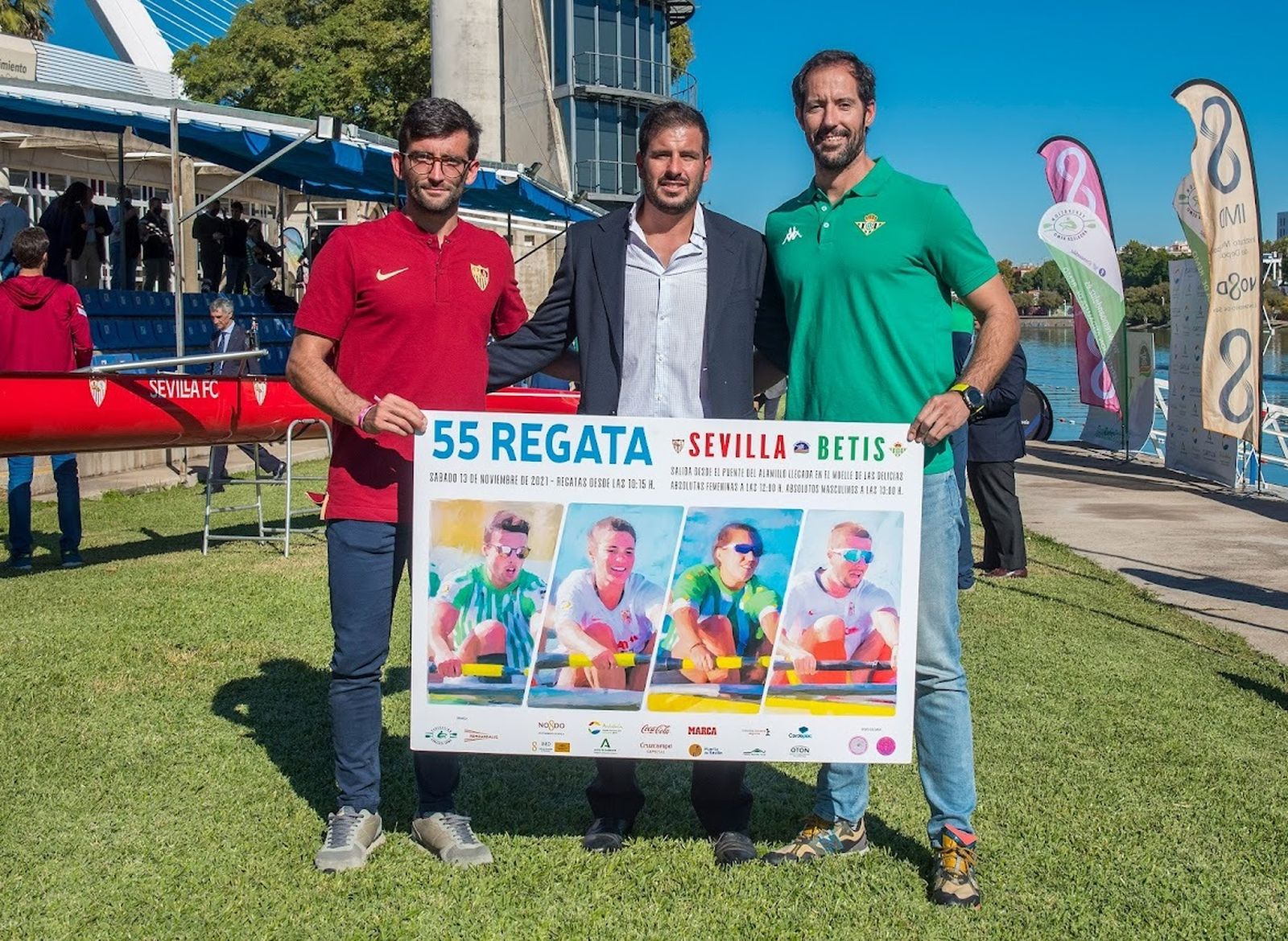 Representantes de los botes del Sevilla y el Betis y posan con el cartel de la prueba.