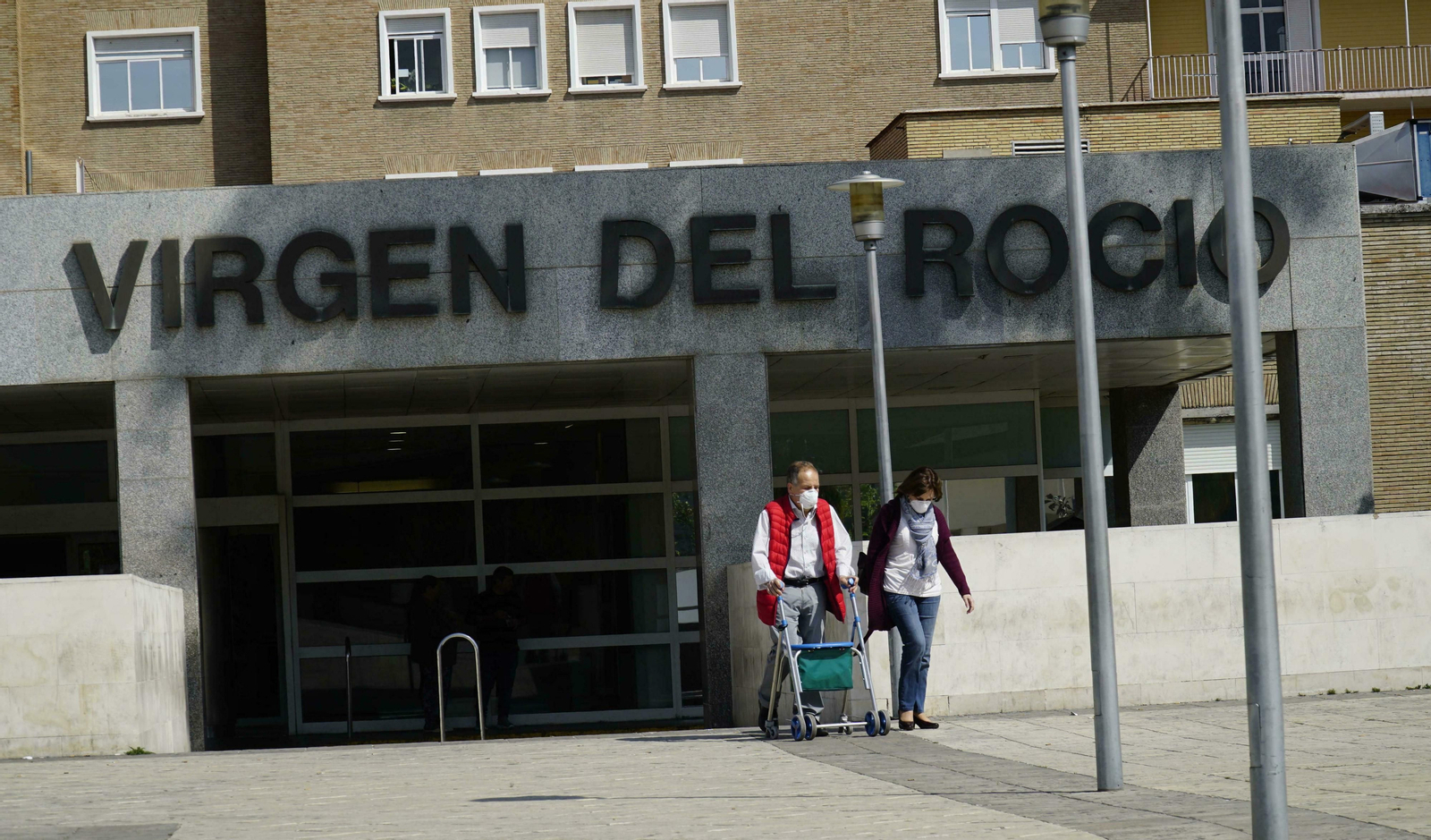 Dos personas salen del Hospital Virgen del Rocío con mascarillas.