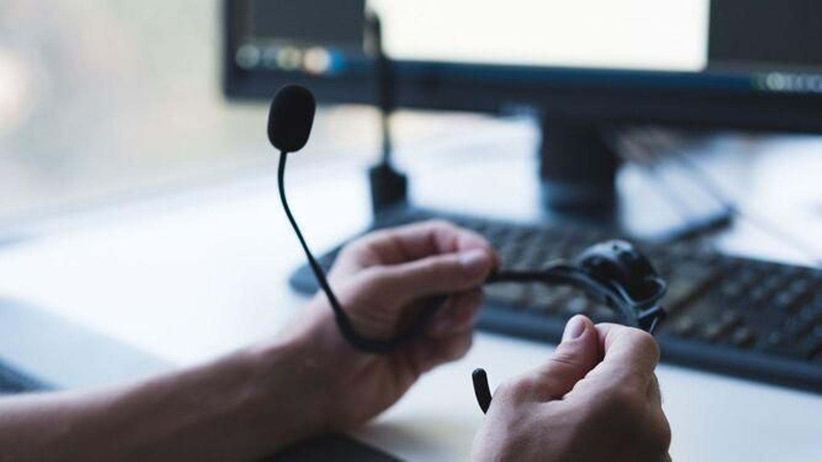 Un operador sostiene sus auriculares con micrófonos utilizados para sus llamadas comerciales