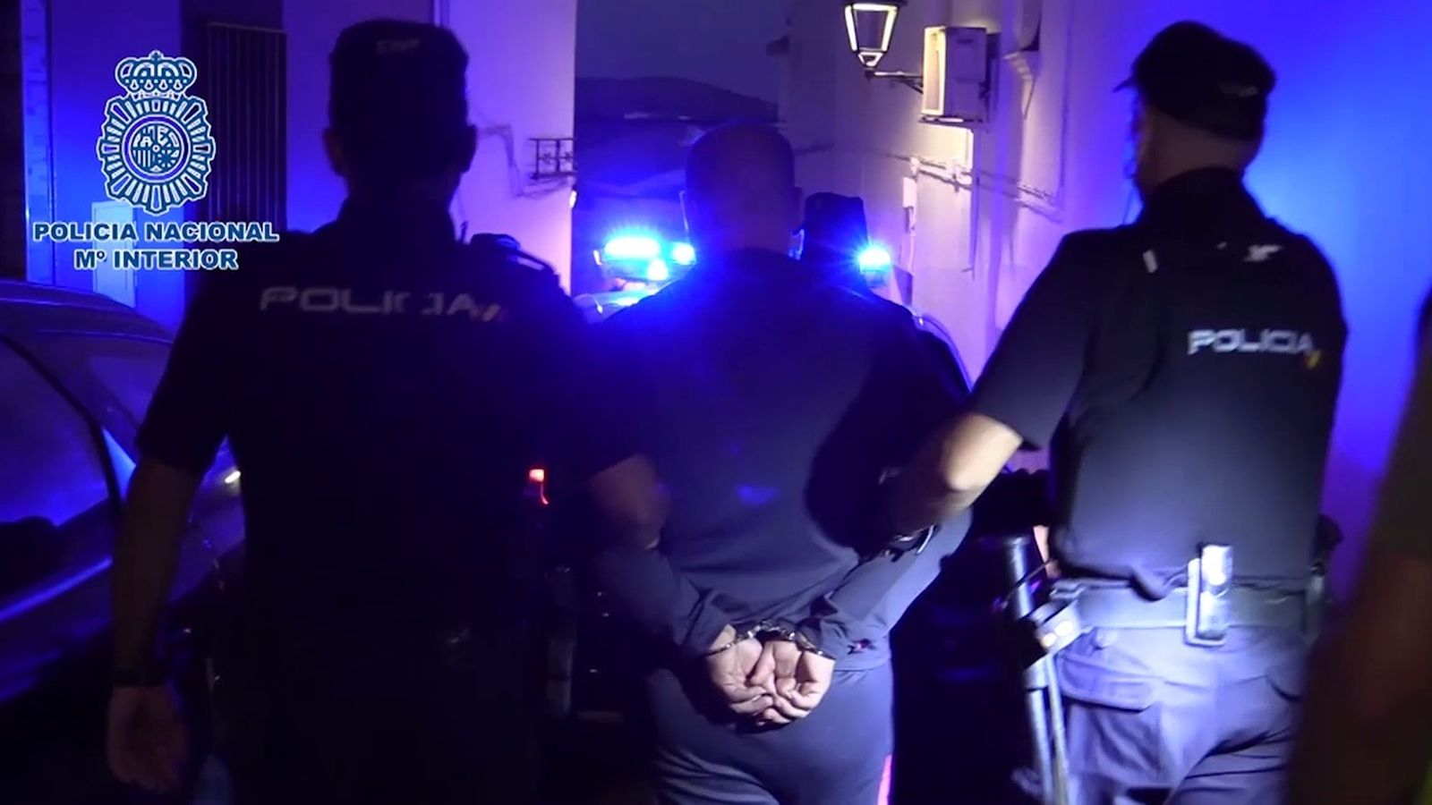 Dos agentes trasladan al detenido al coche.