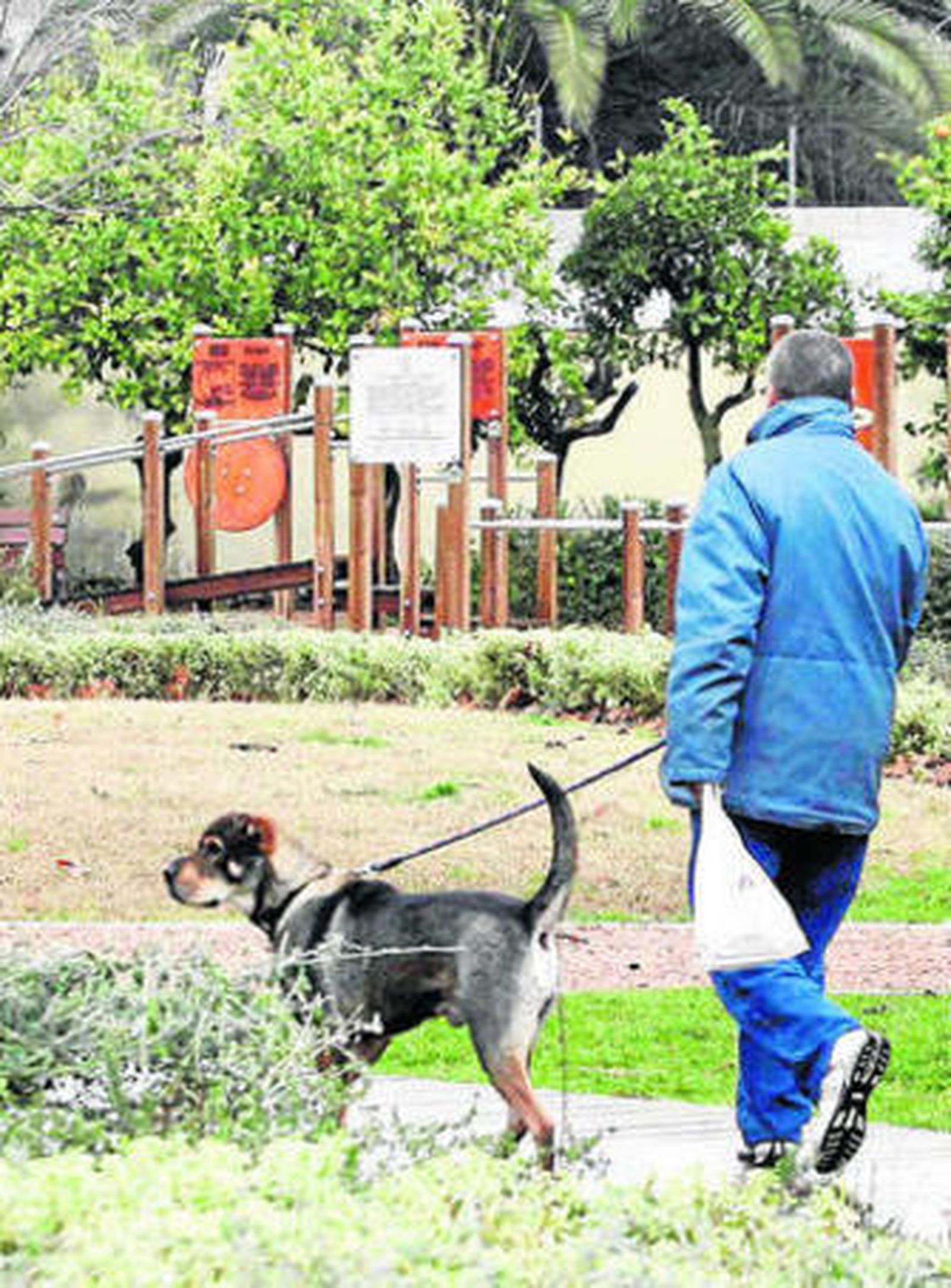 Un hombre pasea a su perro en los jardines de Orive.