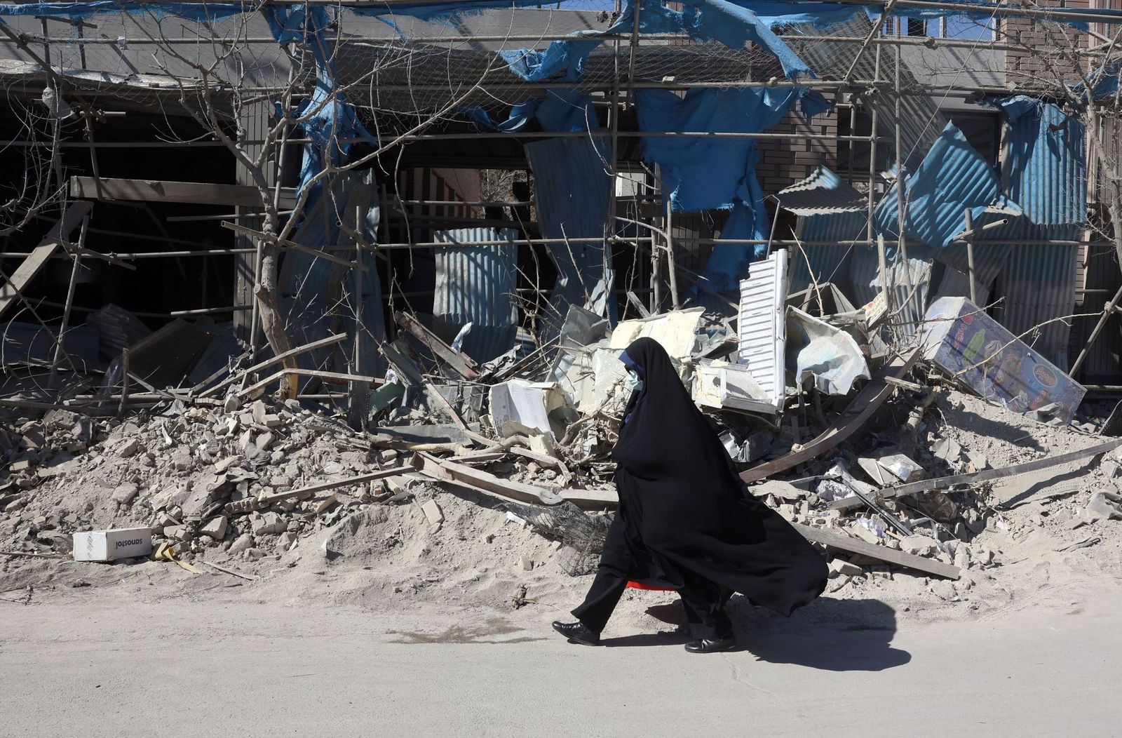 Una iraní pasa ante un edificio destrozado por los bombardeos en Teherán.