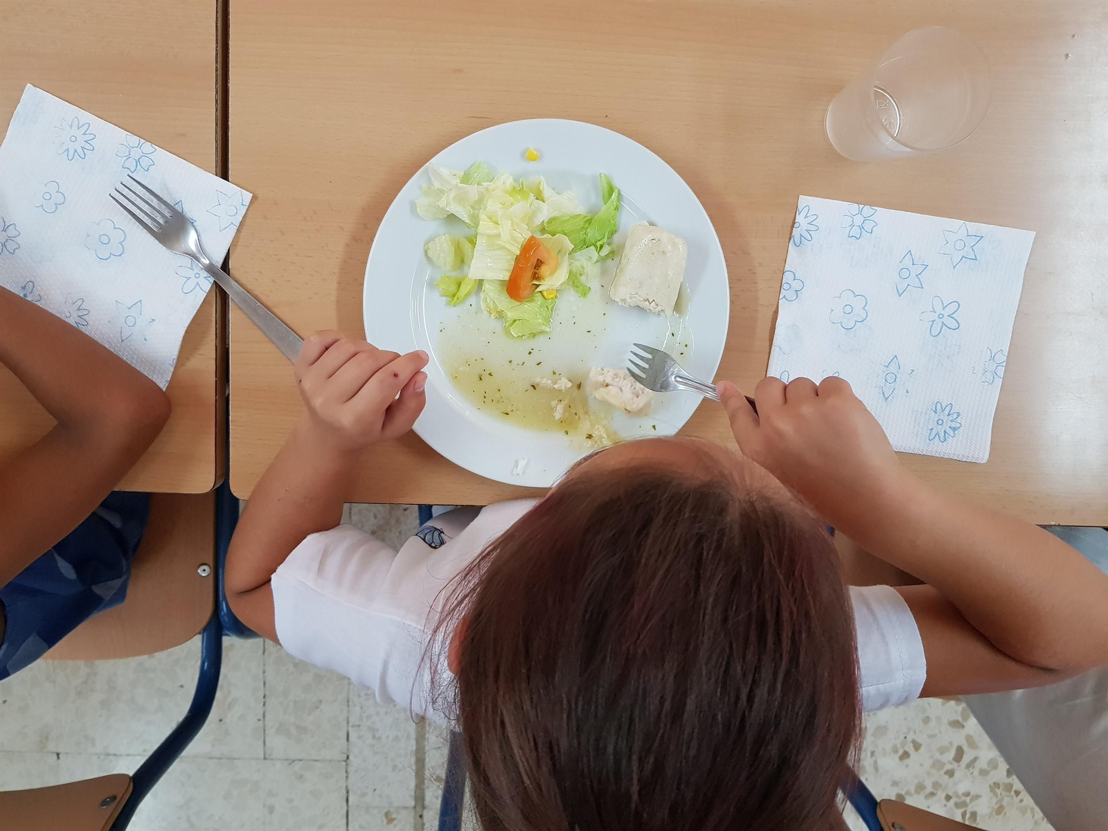 Una niña comiendo en un comedor escolar. Una niña comiendo en un comedor escolar.