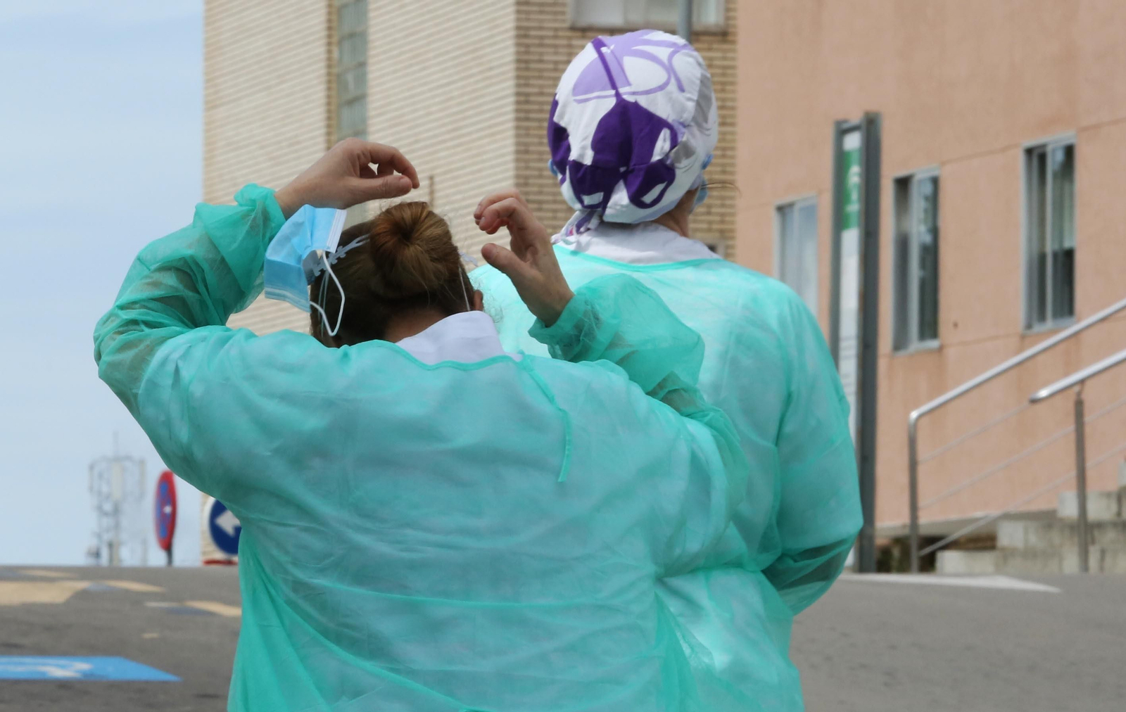 Una profesional se coloca una mascarilla, en el recinto exterior del hospital