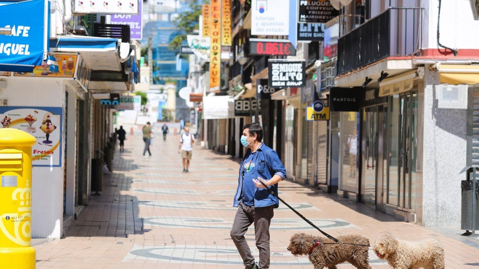 Un hombre con mascarilla camina junto a sus dos perros.