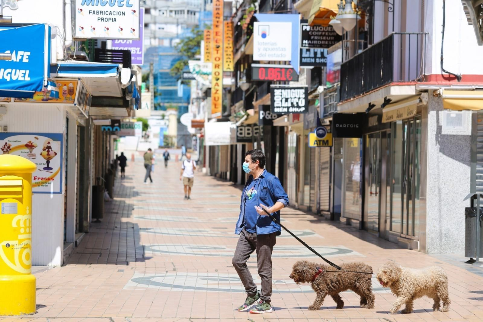 Un hombre con mascarilla camina junto a sus dos perros.
