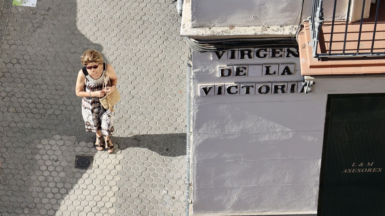 Una transeúnte pasa por delante de la calle Virgen de la Victoria, en Los Remedios.