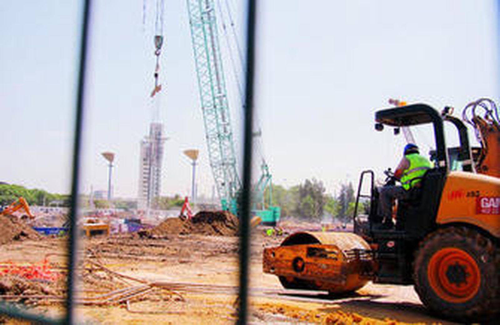 Una apisonadora asienta el terreno donde han comenzado las obras de cimentación del rascacielos en la Cartuja, con la torre Schinder al fondo.