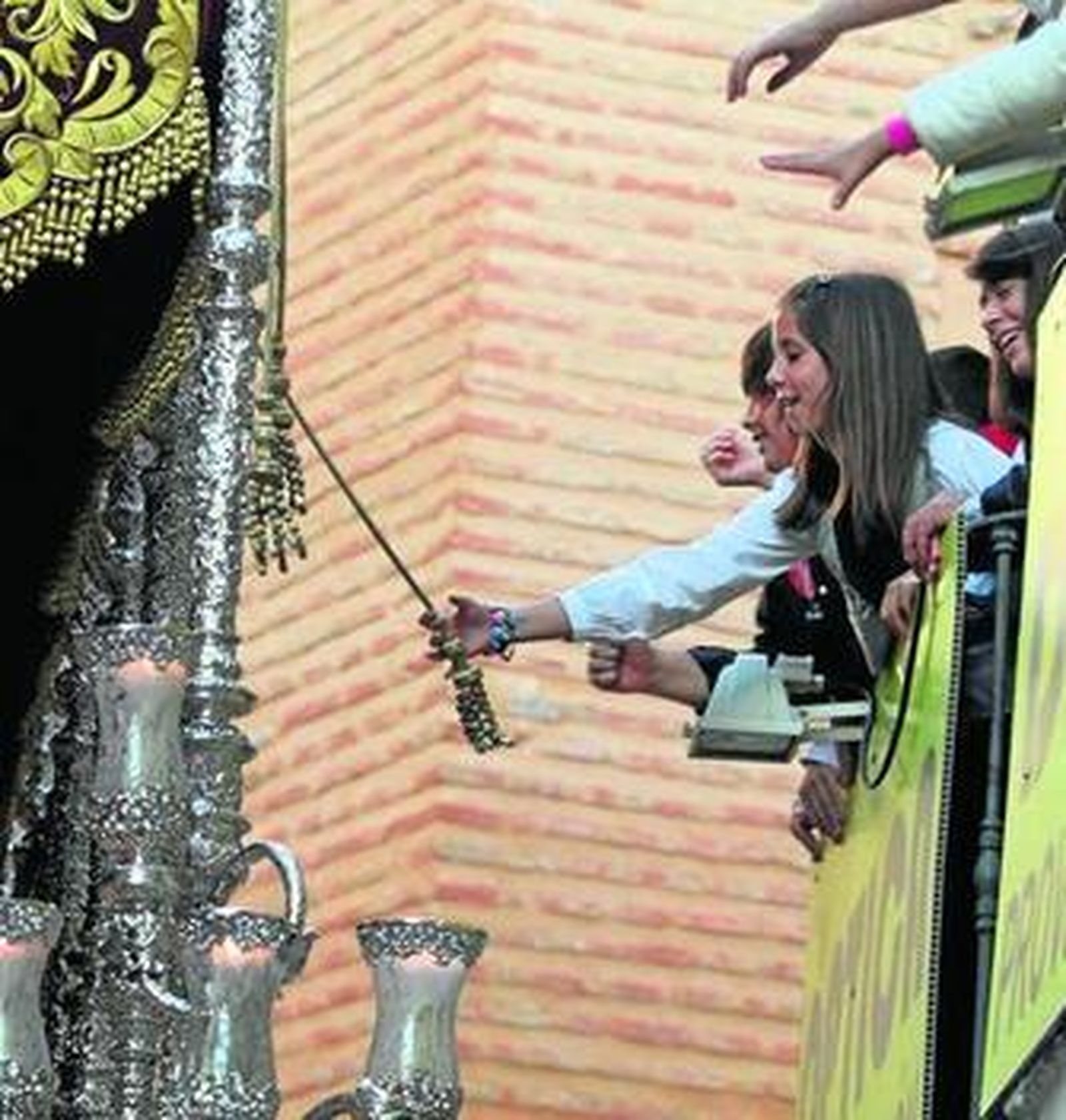 Una niña intenta tocar el palio de la Virgen de la Merced en la calle Granada.