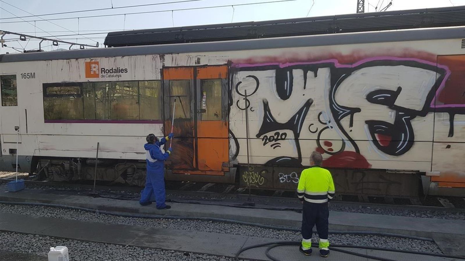 Un trabajador limpia unos grafitis de los trenes.
